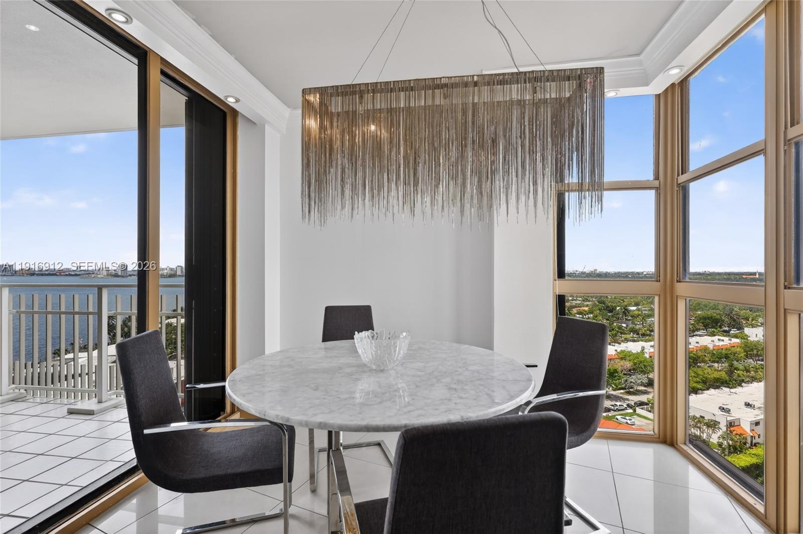 A dining area features a round marble table, four dark chairs, and a chain chandelier — 4000 Towerside Ter # 1612, Miami FL 33138, MIAMI, FL