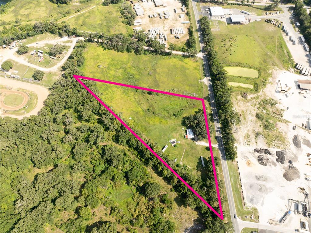 An aerial view shows a triangular plot of land bordered by a road and trees — 7301 NW GAINESVILLE ROAD, OCALA, FL