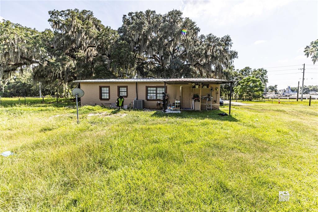 A single-story house with a metal roof sits in a large, grassy field — 7301 NW GAINESVILLE ROAD, OCALA, FL