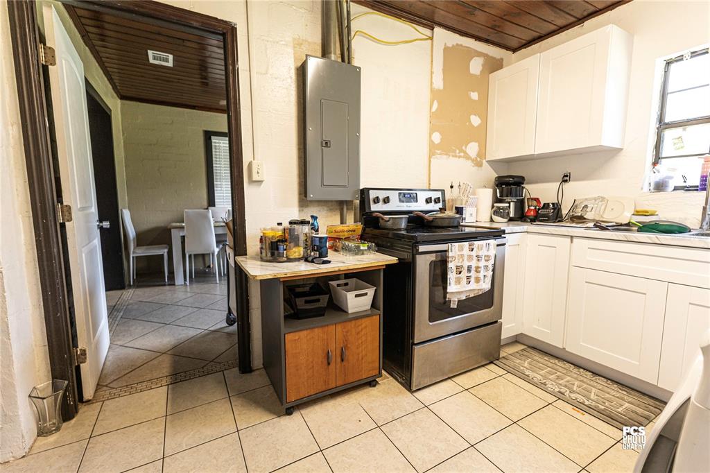 A kitchen features white cabinets, a stainless steel stove, and a gray electrical panel — 7301 NW GAINESVILLE ROAD, OCALA, FL