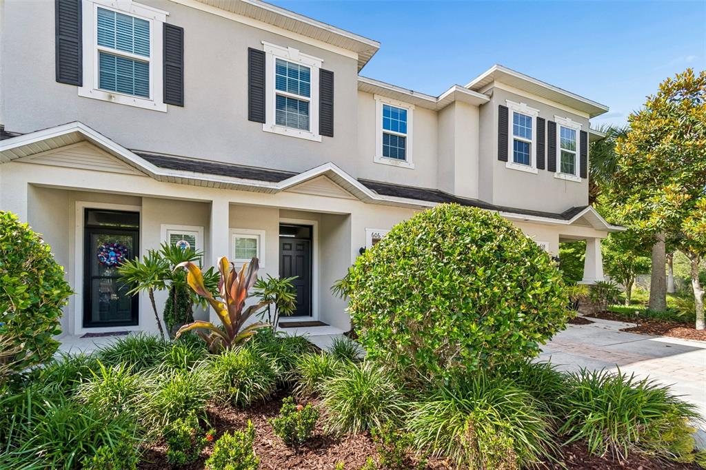 A two-story townhouse exterior with a landscaped front yard and two separate entryways — 606 CABERNET WAY, OLDSMAR, FL