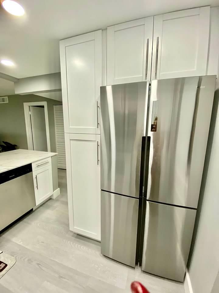 A stainless steel refrigerator stands next to white floor-to-ceiling cabinets in a modern kitchen — 6461 NW 2nd Avenue # 409, Boca Raton FL 33487, BOCA RATON, FL