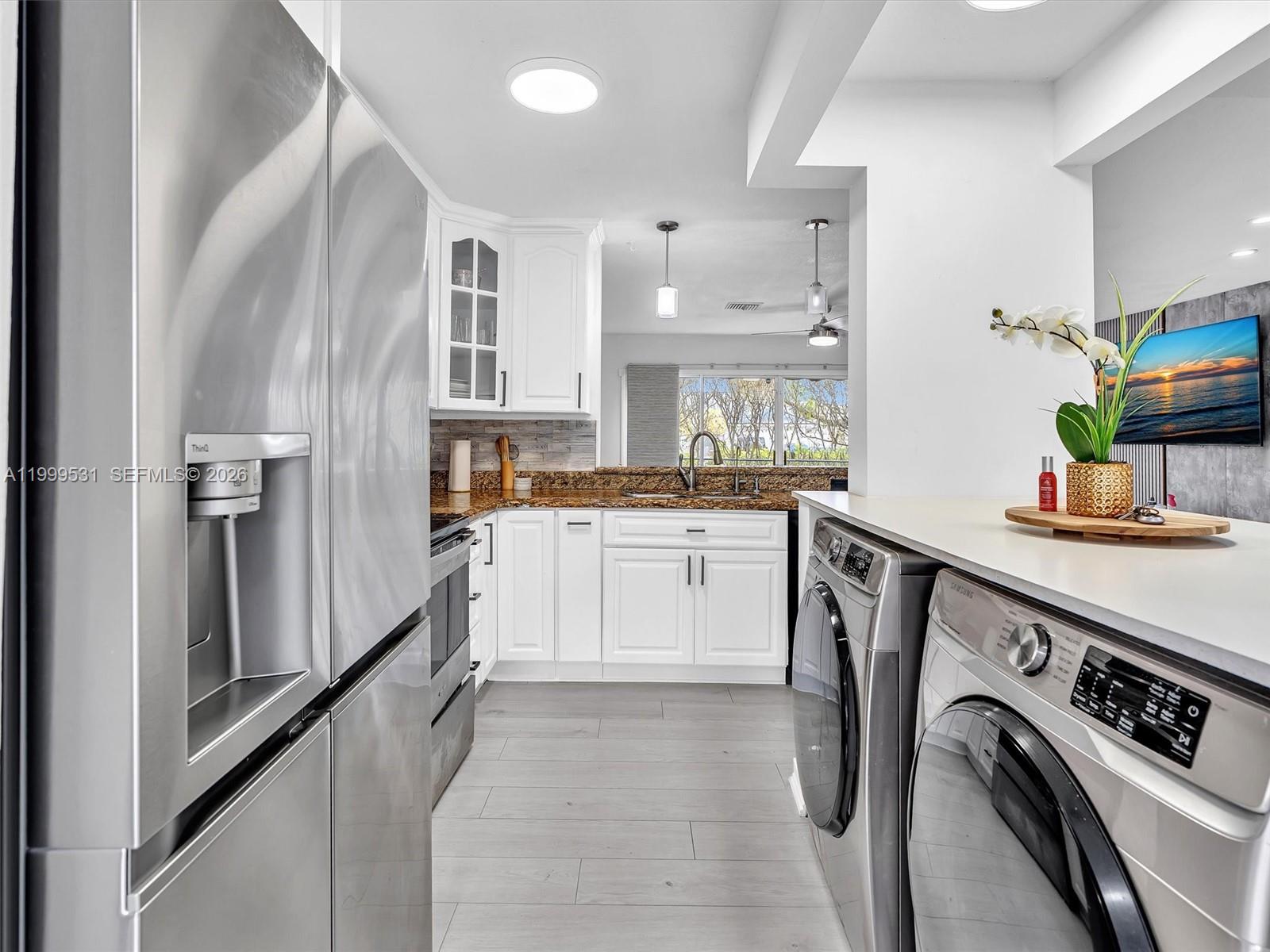 A kitchen features white cabinets, granite countertops, stainless steel appliances, and an adjacent laundry area — 3804 NW 121st Ave, Sunrise FL 33323, SUNRISE, FL