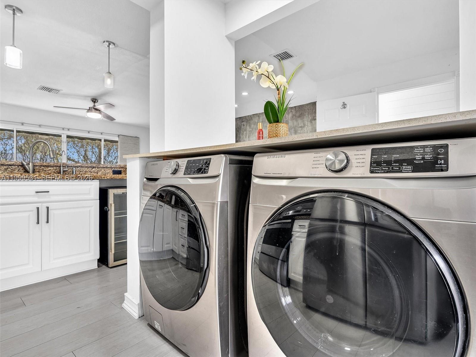 A laundry area features stainless steel Samsung appliances beneath a countertop in a modern kitchen — 3804 NW 121st Ave, Sunrise FL 33323, SUNRISE, FL