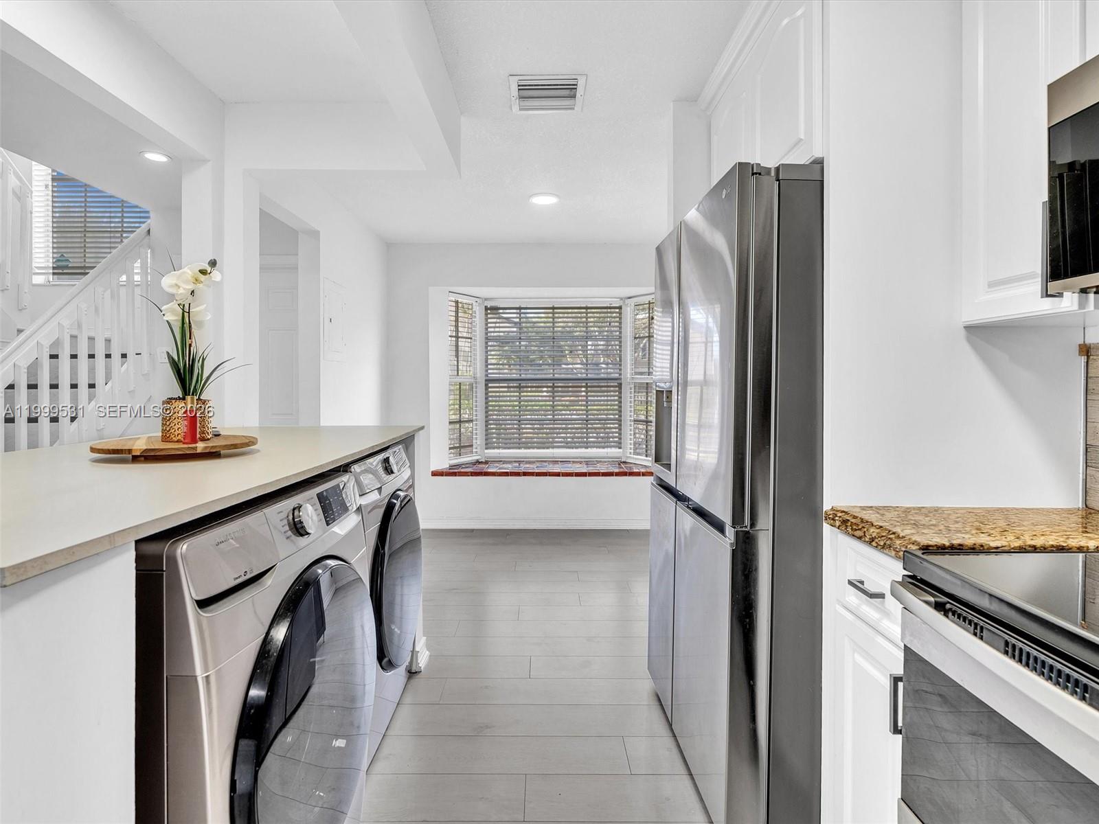 A kitchen features stainless steel appliances, white cabinetry, and a laundry area with a countertop — 3804 NW 121st Ave, Sunrise FL 33323, SUNRISE, FL