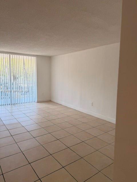 An empty room features light-colored tile flooring, white walls, and a large sliding glass door — 498 NW 165th St Rd # 204, Miami FL 33169, MIAMI, FL