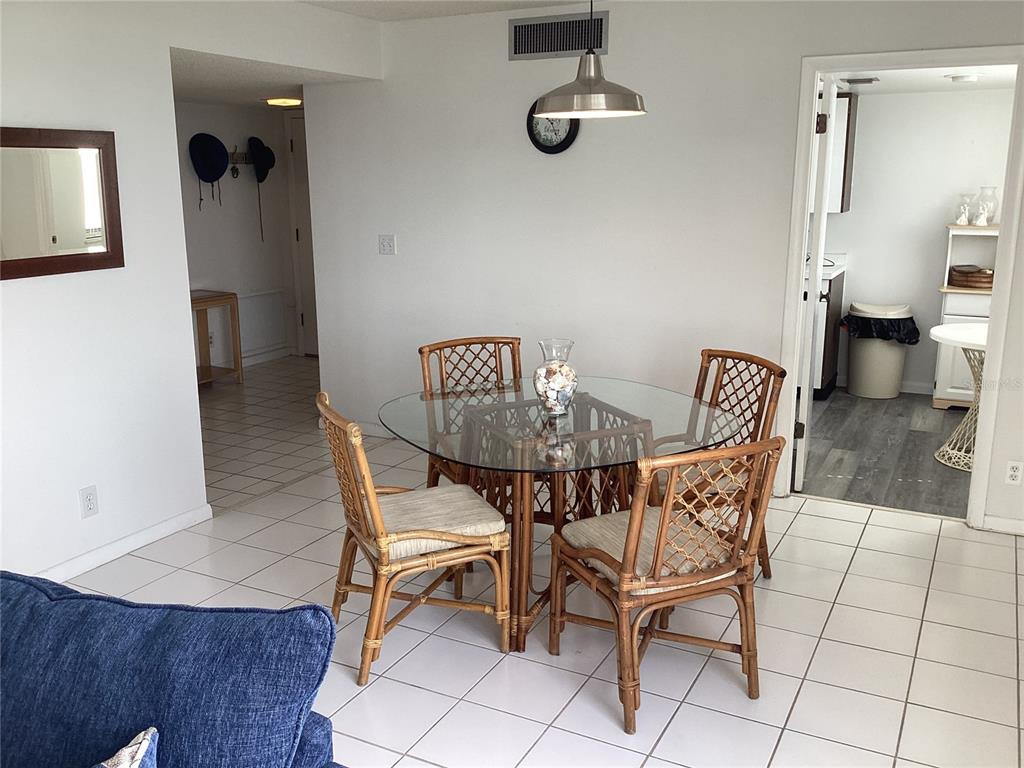 A dining area features a glass-topped rattan table and four matching chairs on tiled floors — 1430 GULF BOULEVARD UNIT 404, CLEARWATER BEACH, FL