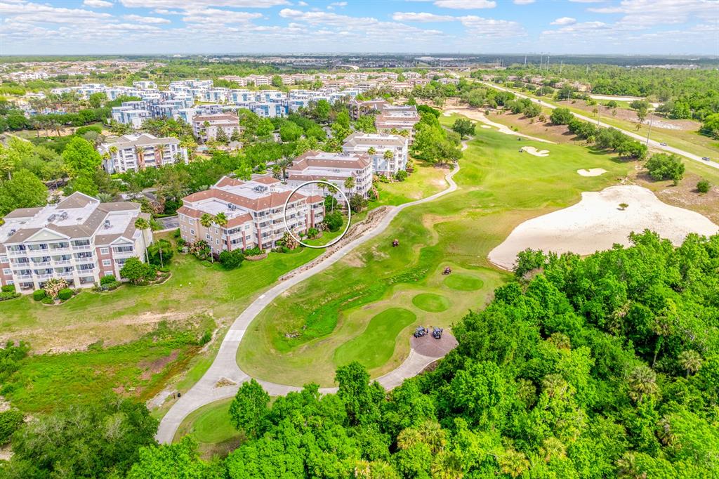 An aerial view shows a multi-story apartment building situated next to a golf course — 7612 CABANA COURT UNIT 201, REUNION, FL