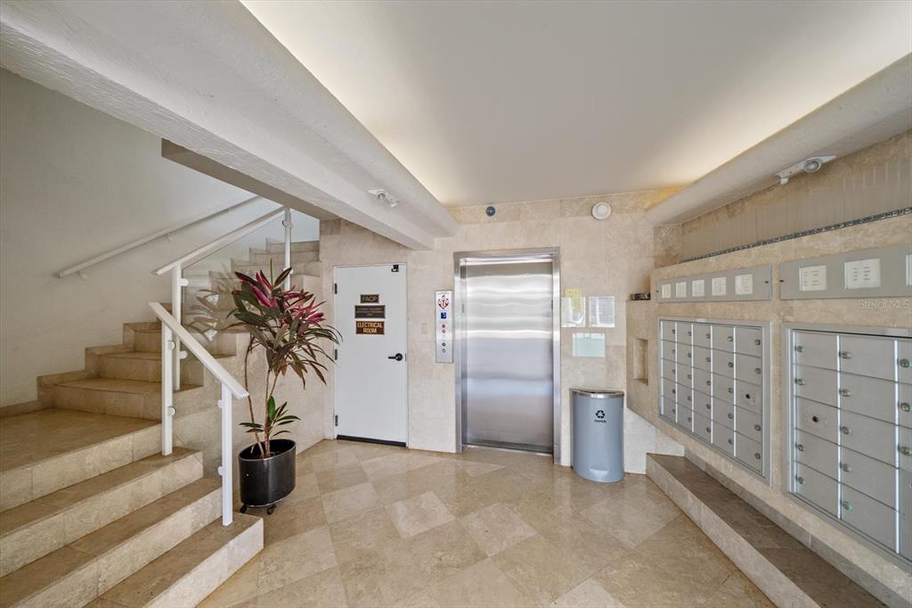 A lobby area features a staircase, an elevator, a row of mailboxes, and tile flooring — 100 SANDS POINT ROAD UNIT 303, LONGBOAT KEY, FL