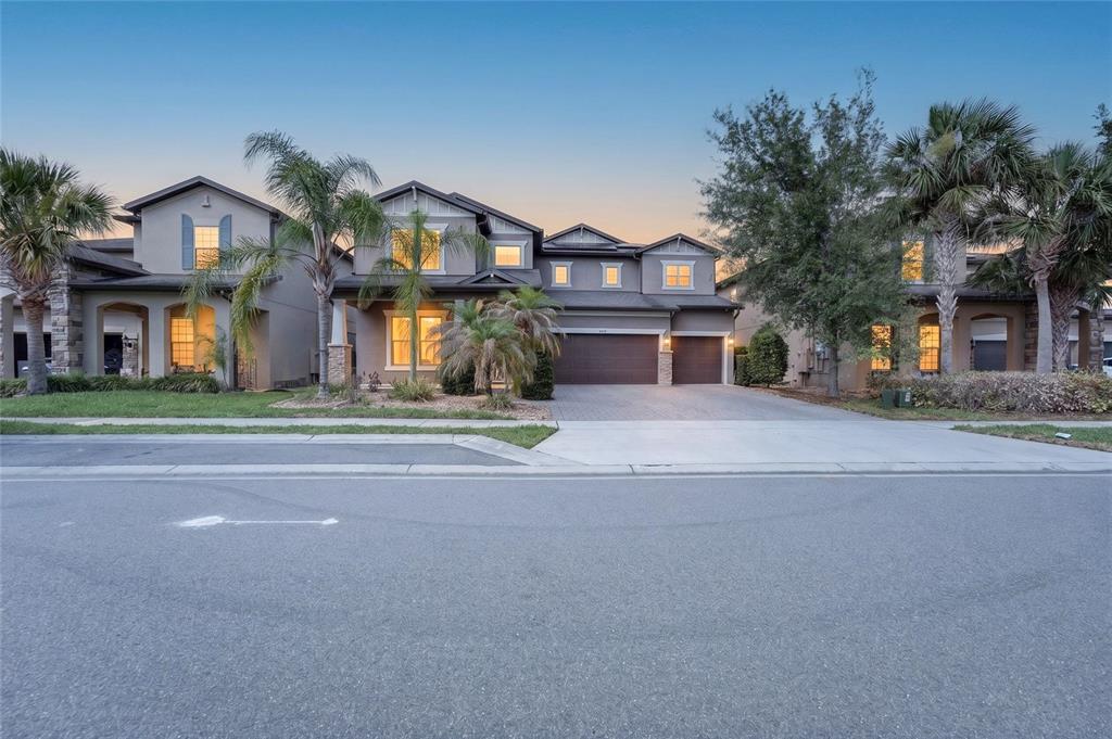 A two-story suburban house with a three-car garage and palm trees in the front yard — 9210 ROYAL ESTATES BOULEVARD, ORLANDO, FL