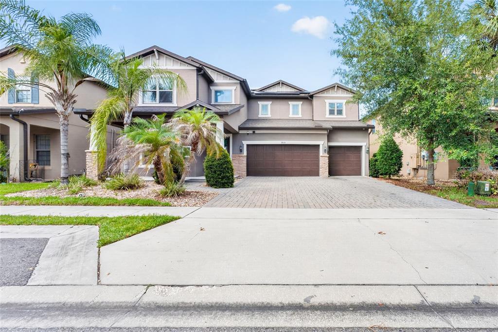 A two-story house with a three-car garage, a paved driveway, and palm trees in front — 9210 ROYAL ESTATES BOULEVARD, ORLANDO, FL
