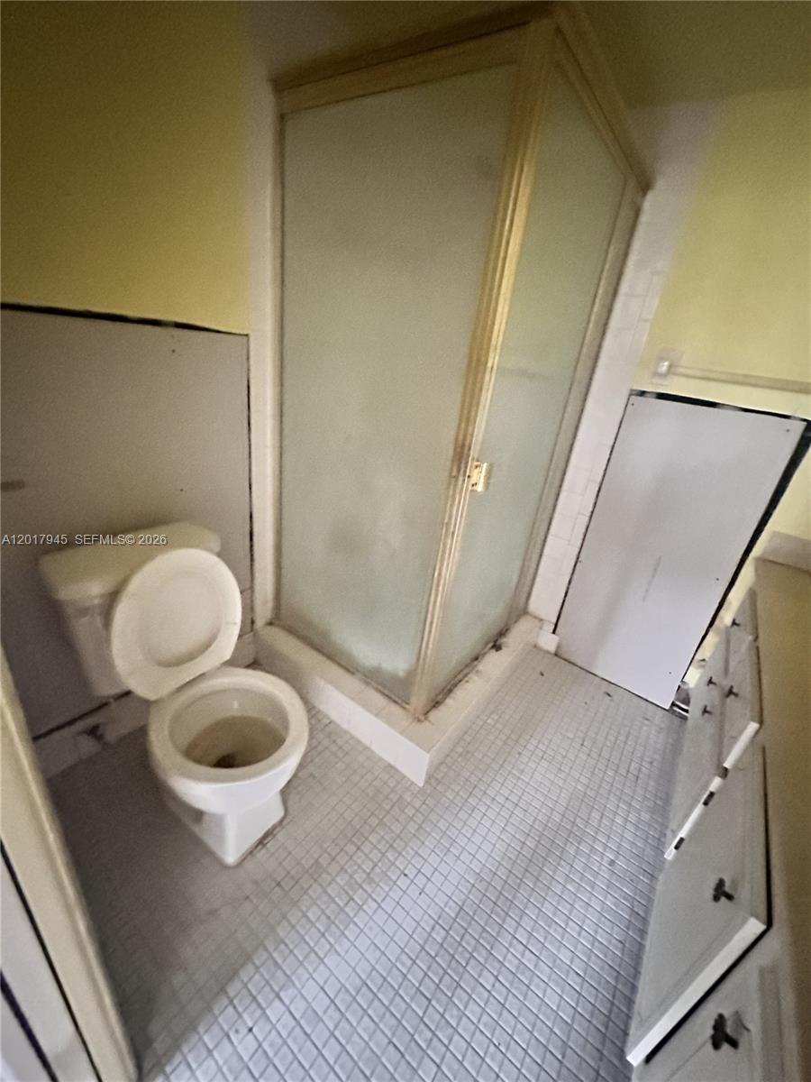 A bathroom features a toilet, a corner shower stall, and a vanity with white cabinets — 6001 NW 61st Ave # 111, Tamarac FL 33319, TAMARAC, FL