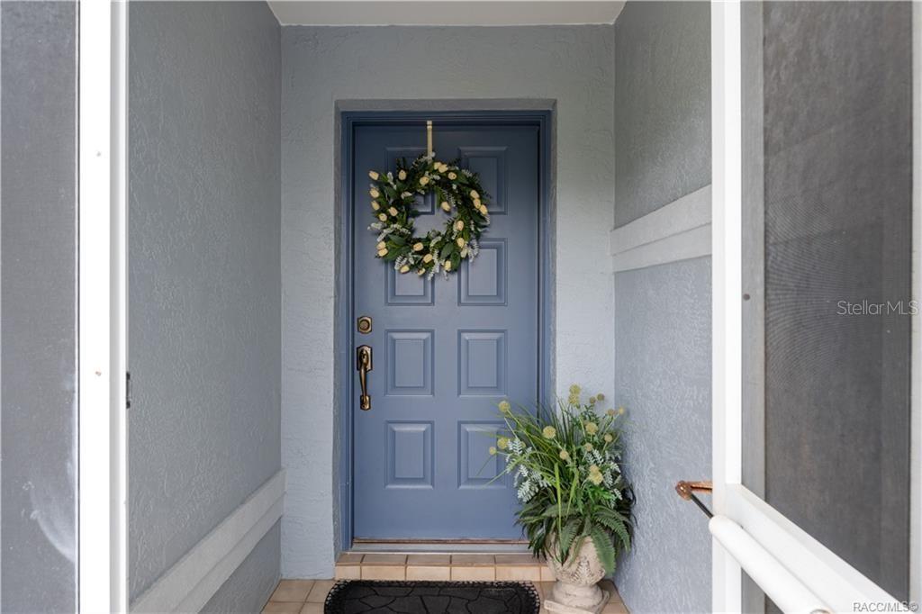 A blue front door with a wreath and a potted plant sits in an entryway — 4271 N STEWART WAY, BEVERLY HILLS, FL