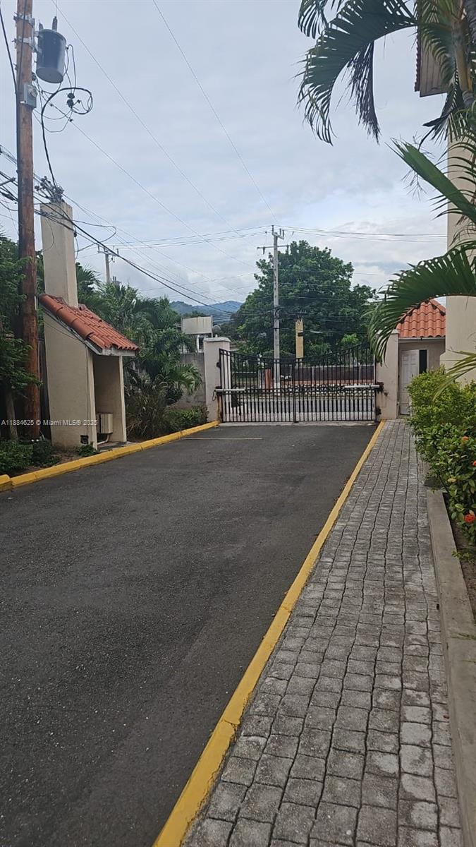 A paved driveway leads to a gated entrance with a small guardhouse and landscaping — 00 Waterloo Rd, Kingston Jamaica # 01, NA, NA