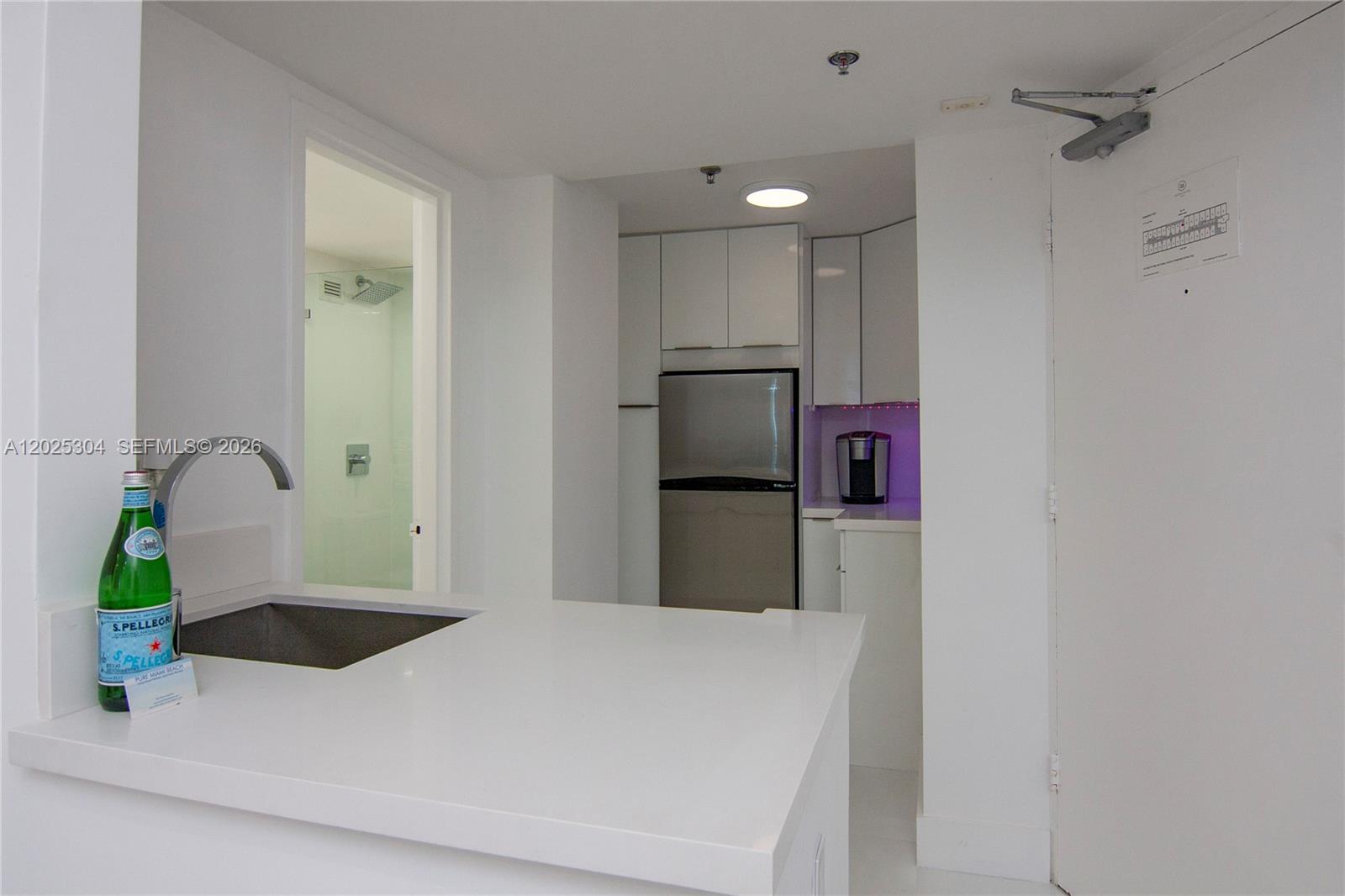 A kitchen area features white cabinetry, stainless steel appliances, and a white countertop — 5445 Collins Ave # 1730, Miami Beach FL 33140, MIAMI BEACH, FL