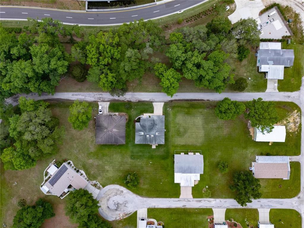 An aerial view shows several houses with driveways and trees surrounded by a grassy landscape — LOT 61 BLK C LEXINGTON CIRCLE, WILDWOOD, FL