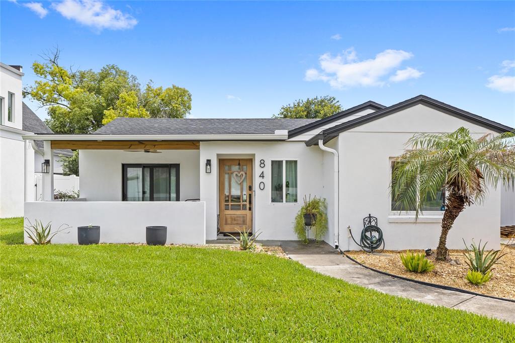 A white single-story house features a covered front porch, a wooden door, and landscaping — 840 W CANTON AVENUE, WINTER PARK, FL