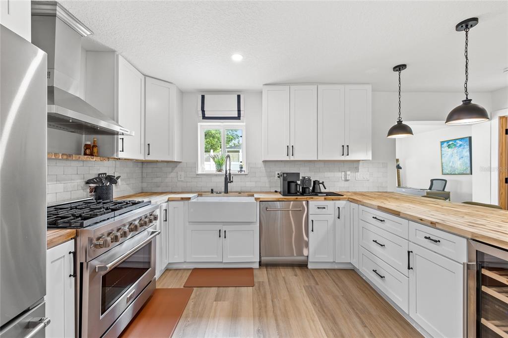 A kitchen features white cabinetry, butcher block countertops, a farmhouse sink, and stainless steel appliances — 840 W CANTON AVENUE, WINTER PARK, FL