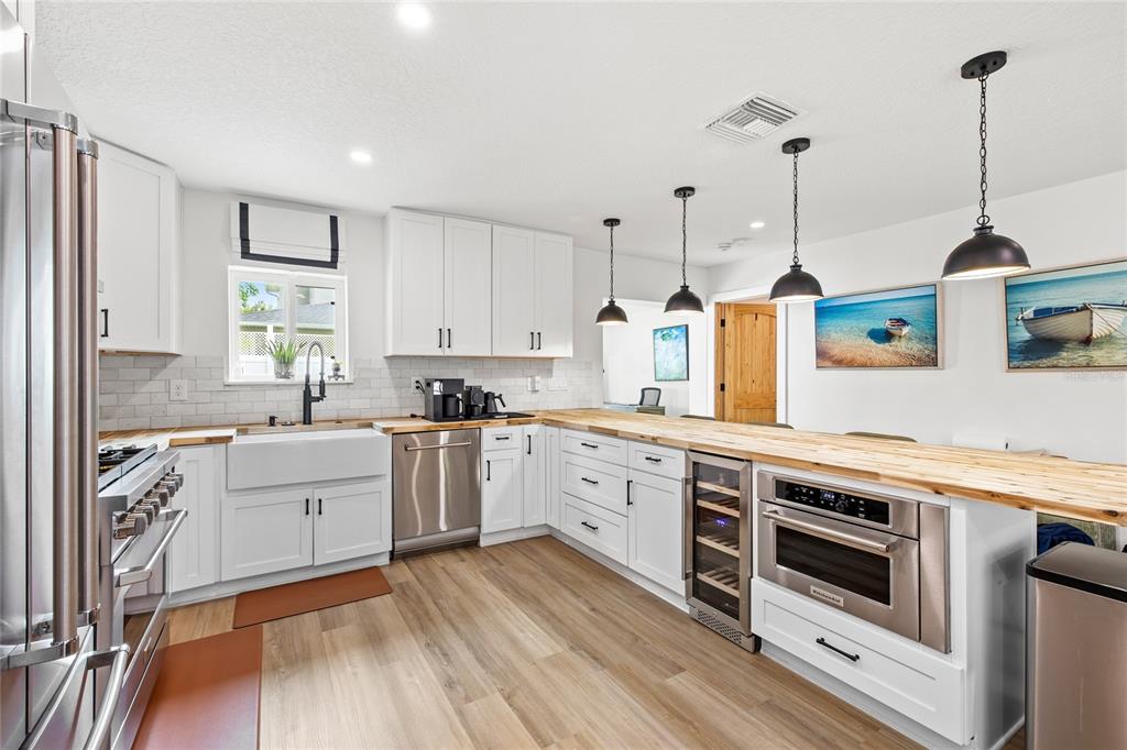 A kitchen features white cabinetry, a farmhouse sink, wood countertops, and stainless steel appliances — 840 W CANTON AVENUE, WINTER PARK, FL