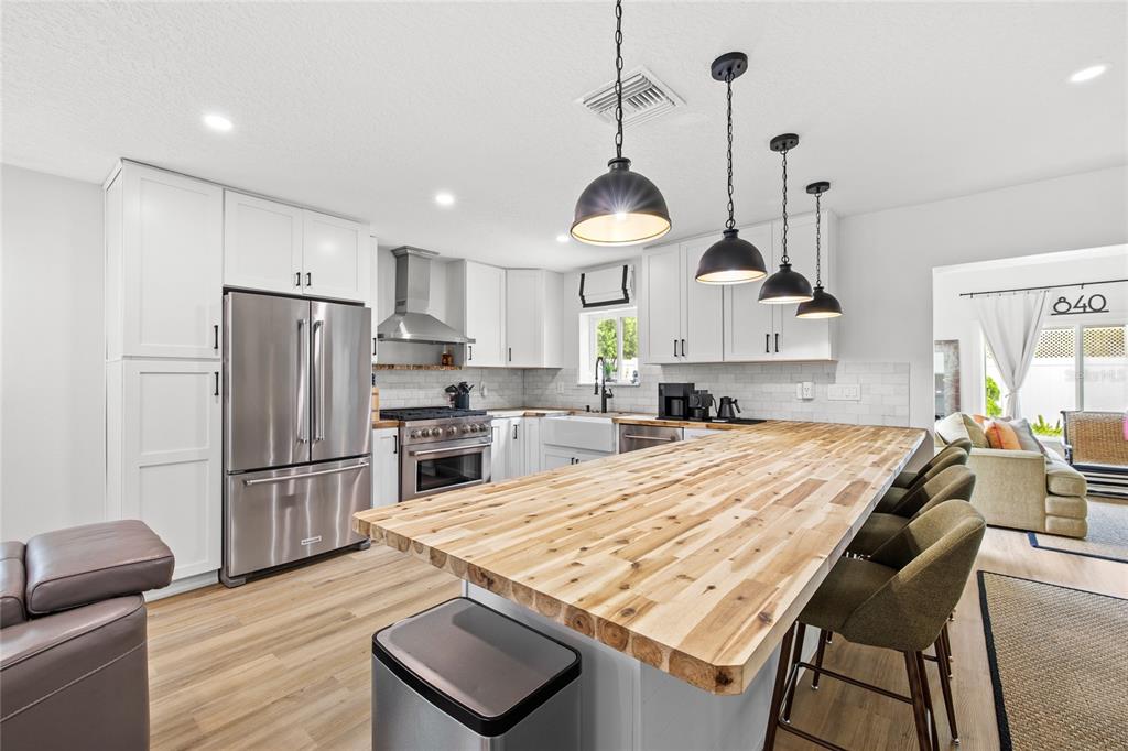 A kitchen features white cabinetry, a large wooden island, and three black pendant lights — 840 W CANTON AVENUE, WINTER PARK, FL