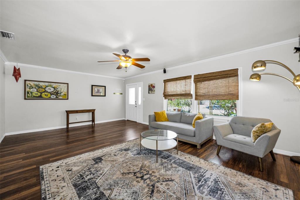 A living room features hardwood floors, a gray sofa and armchair, and a patterned area rug — 4994 17TH AVENUE N, ST PETERSBURG, FL