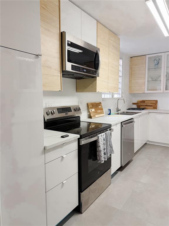 A modern kitchen features white and light wood cabinets, stainless steel appliances, and tile flooring — . ELEMI UNIT 114, GUAYNABO, PR