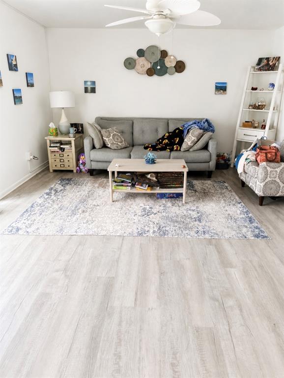 A living room features a gray sofa, a coffee table, and a light-colored wood floor — 563 FAIRWAYS DRIVE UNIT A, OCALA, FL