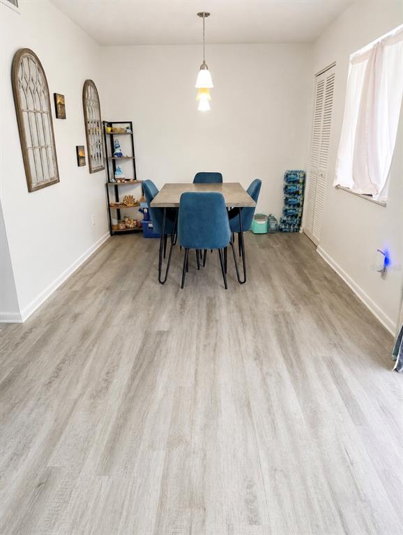 A dining area features a square table with four blue chairs and light wood-look flooring — 563 FAIRWAYS DRIVE UNIT A, OCALA, FL