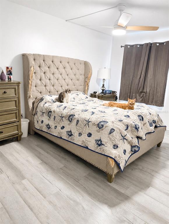 A bedroom features a tufted beige headboard, a seashell-patterned quilt, and two cats on the bed — 563 FAIRWAYS DRIVE UNIT A, OCALA, FL
