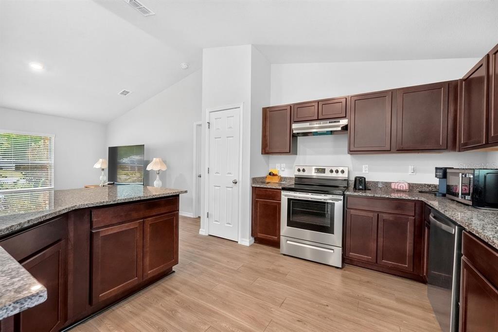 A kitchen with dark wood cabinets, granite countertops, and stainless steel appliances — 3 KARANDA COURT, PALM COAST, FL