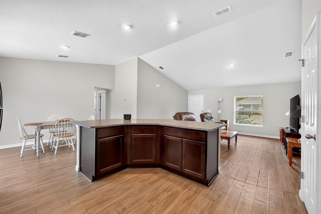 An open-concept living and dining area features a dark wood kitchen island with granite countertops — 3 KARANDA COURT, PALM COAST, FL