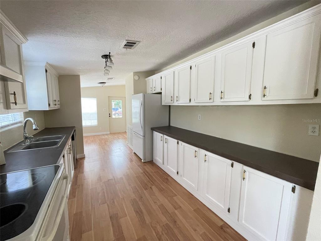 A kitchen features white cabinets, dark countertops, and light wood flooring — 13716 NE COUNTY ROAD 1471, WALDO, FL