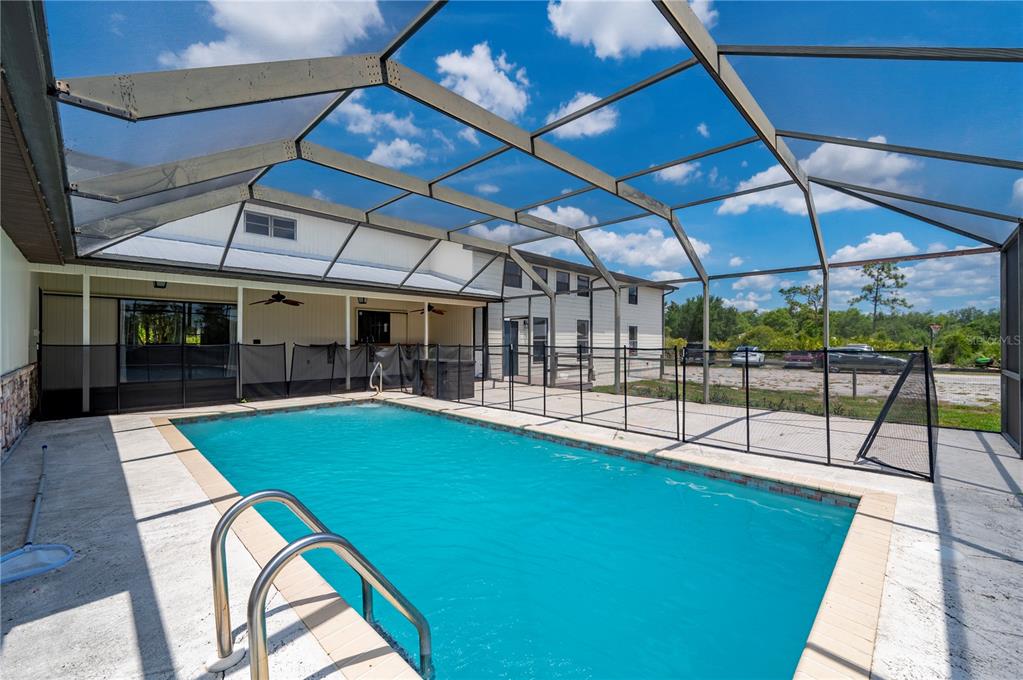 A swimming pool with a metal ladder sits inside a screened-in patio enclosure — 5674 BLACKJACK COURT S, PUNTA GORDA, FL
