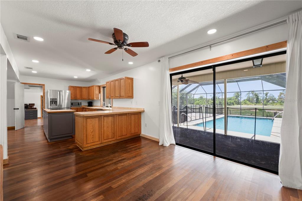 A kitchen with wood cabinets and a breakfast bar overlooks a pool and patio area — 5674 BLACKJACK COURT S, PUNTA GORDA, FL