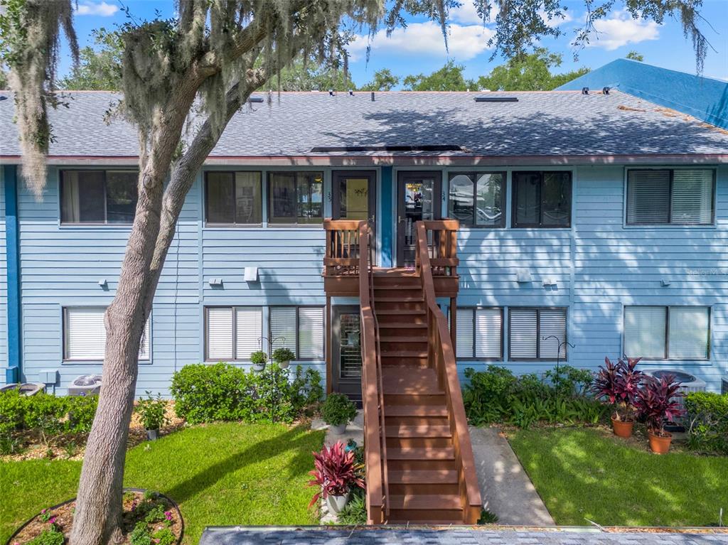 A two-story blue apartment building features a central wooden staircase leading to upper-level entrances — 608 S MAIN AVENUE UNIT 35, MINNEOLA, FL