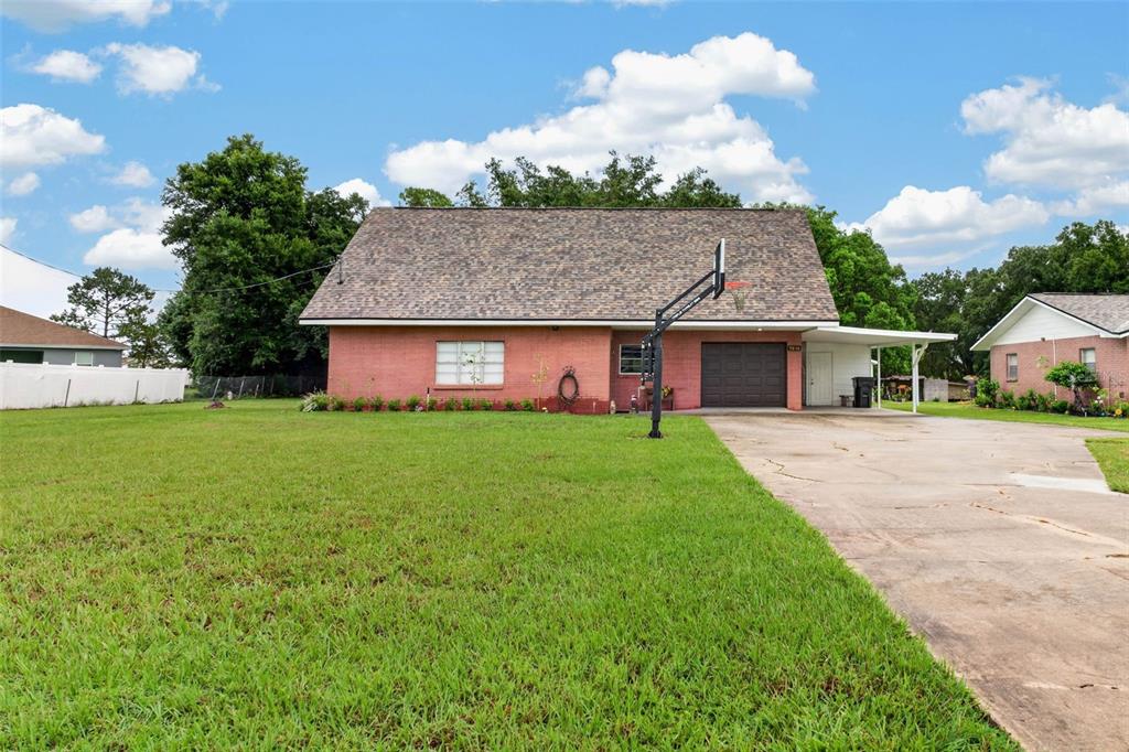 A single-story red brick house with a steep roof, attached carport, and a front lawn — 5838 OLD BARTOW EAGLE LAKE ROAD, WINTER HAVEN, FL
