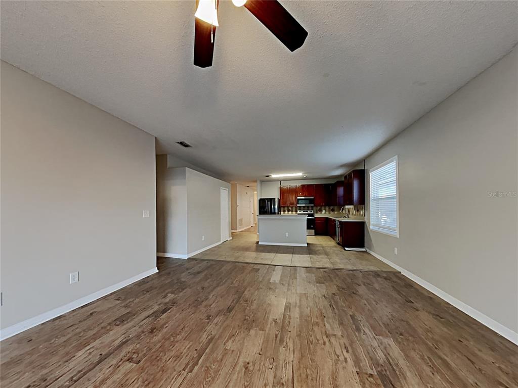 An open-concept living area features wood-look flooring, a ceiling fan, and a kitchen with dark cabinets — 716 KNOLLWOOD DRIVE, DAVENPORT, FL