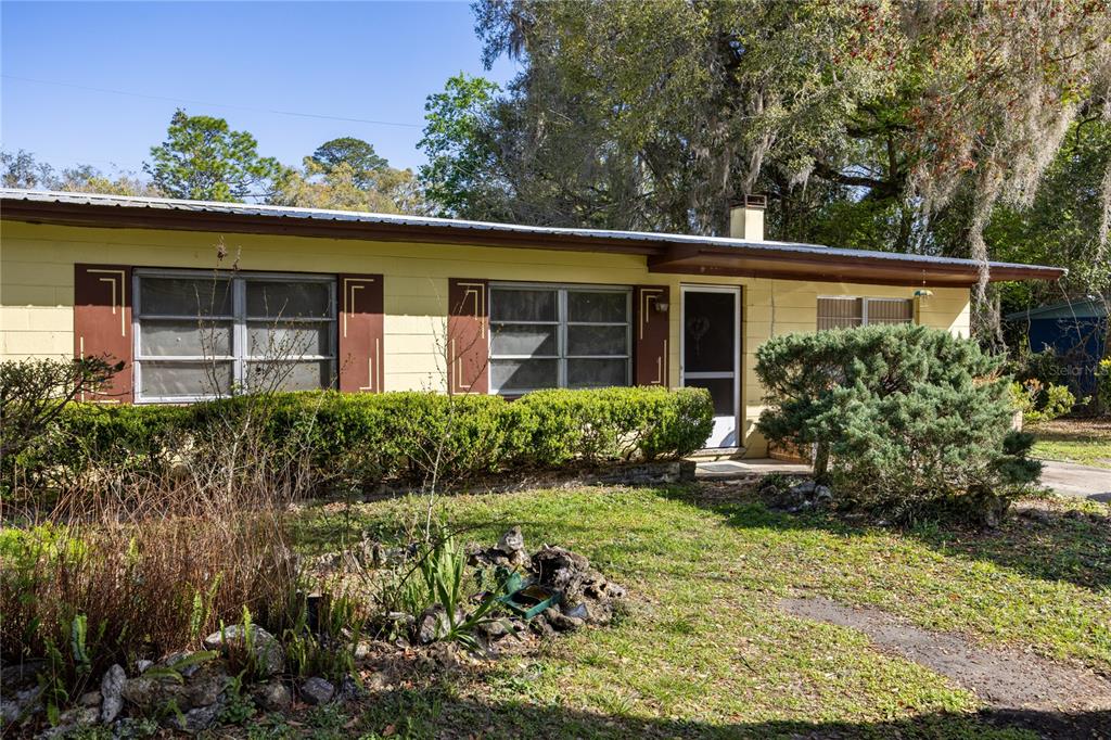 A single-story yellow house with a metal roof and a front yard with landscaping — 1610 SE 25TH AVENUE, GAINESVILLE, FL