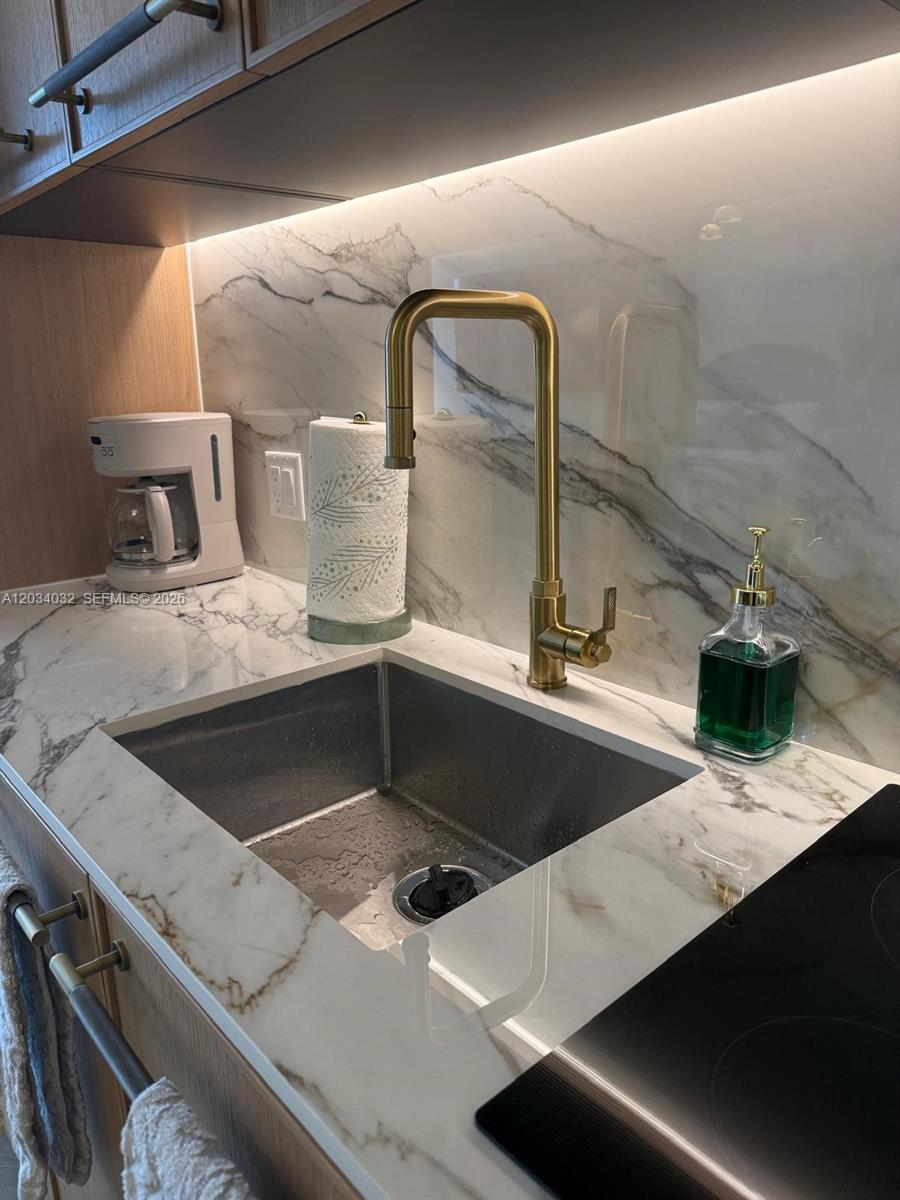 A kitchen sink area features a gold faucet, marble-patterned countertops, and a backsplash — 2700 NW 2ND AVE # 209, Miami FL 33127, MIAMI, FL