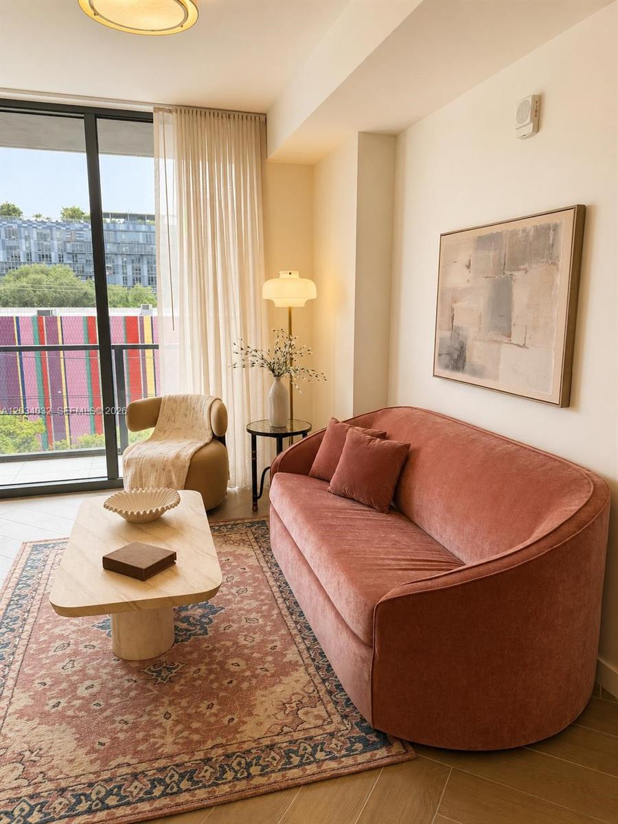 A living room features a pink velvet sofa, a coffee table, and a floor lamp — 2700 NW 2ND AVE # 209, Miami FL 33127, MIAMI, FL
