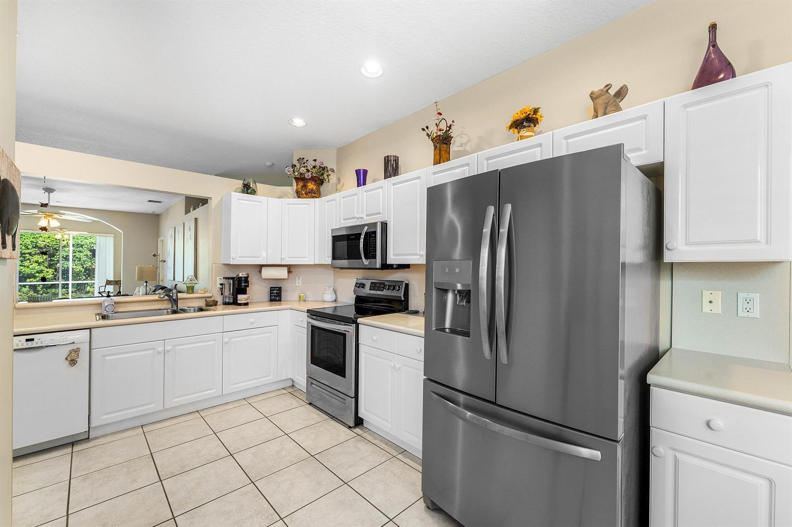 A kitchen with white cabinets, stainless steel appliances, and light-colored tile flooring — 10760 Royal Caribbean Circle, Boynton Beach FL 33437, BOYNTON BEACH, FL