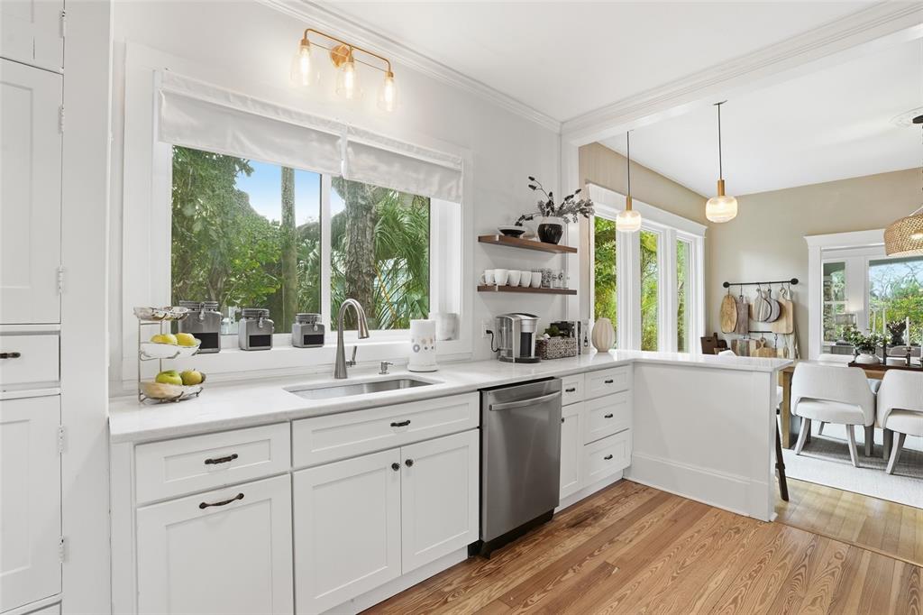 A bright kitchen features white cabinets, stainless steel appliances, and a window overlooking lush greenery — 1473 BARCELONA AVENUE, FORT MYERS, FL