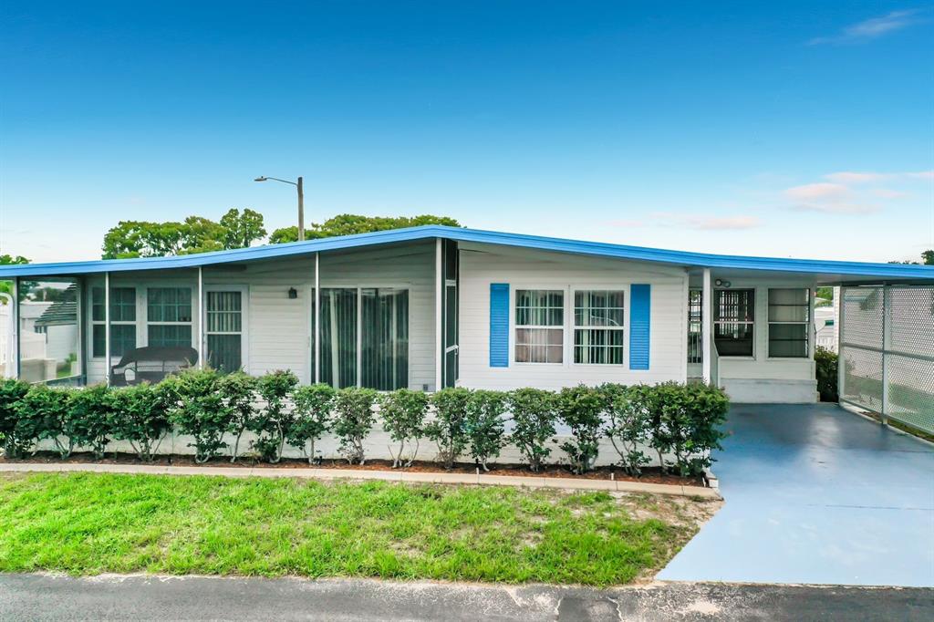 A single-story manufactured home with a blue roof, white siding, and an attached carport — 176 SUNSET DRIVE, LEESBURG, FL
