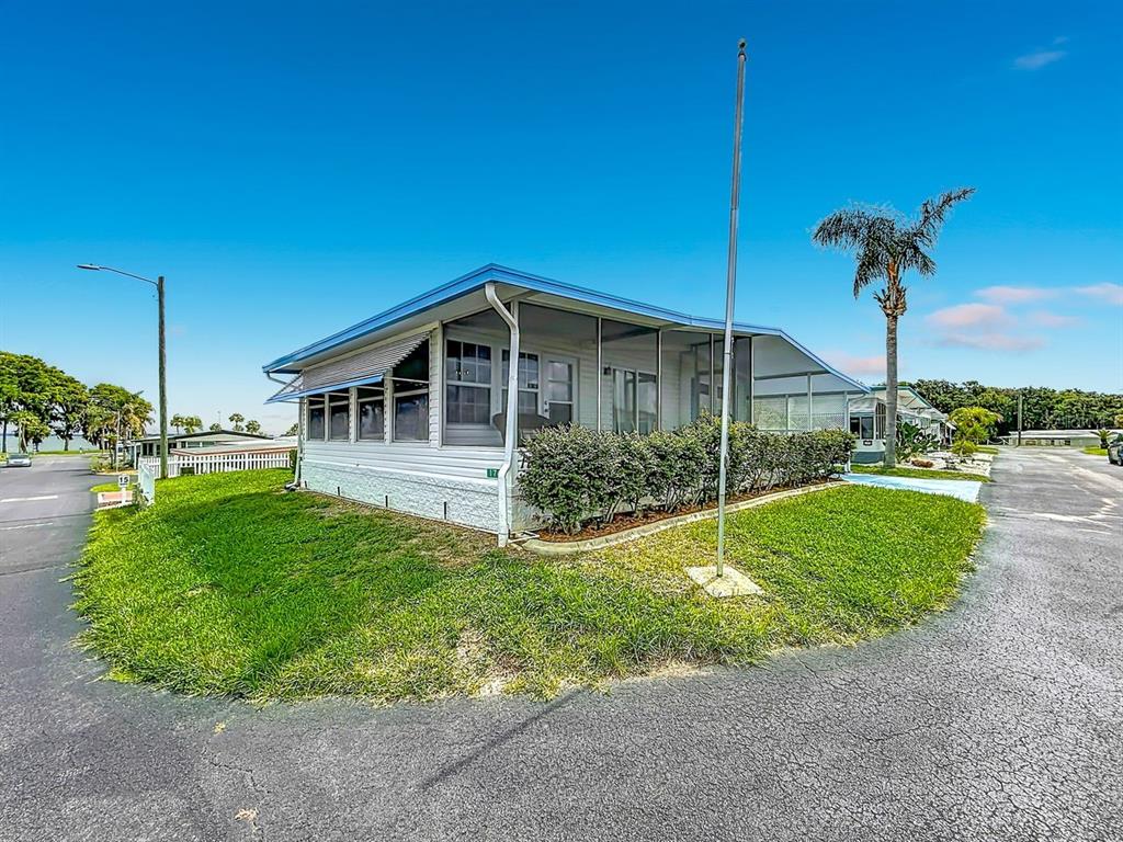 A white manufactured home with a screened-in porch sits on a corner lot — 176 SUNSET DRIVE, LEESBURG, FL