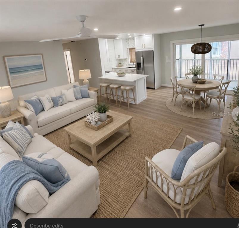 An open-concept living and dining area features light wood floors, white cabinetry, and coastal decor — 3755 S SCHOOL AVENUE UNIT 54, SARASOTA, FL