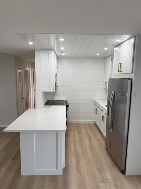A modern kitchen features white cabinetry, gold hardware, a quartz countertop, and shiplap wall paneling — 3755 S SCHOOL AVENUE UNIT 54, SARASOTA, FL
