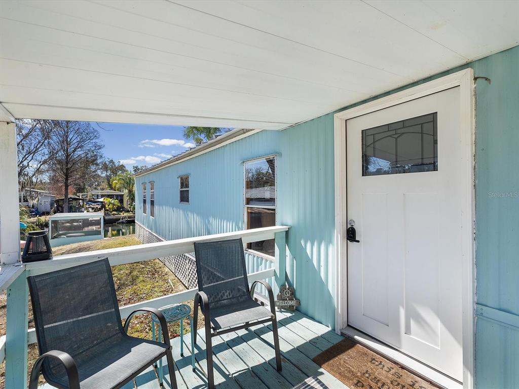 A light blue mobile home exterior features a covered porch with two chairs and a door — 6419 W RICHARD DRIVE, WEEKI WACHEE, FL