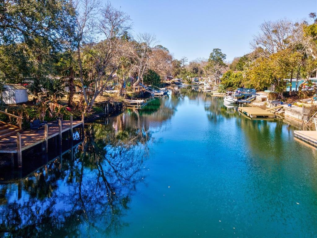 A canal flows between residential properties with wooden docks and trees under a clear sky — 6419 W RICHARD DRIVE, WEEKI WACHEE, FL