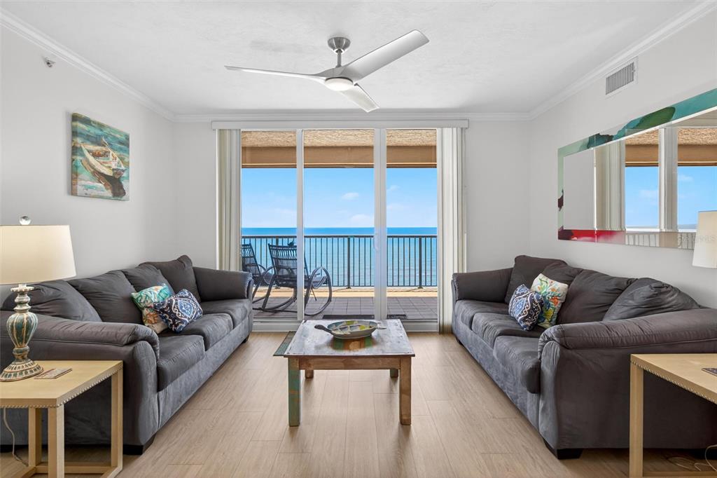 A living room features two gray sofas, a wooden coffee table, and a balcony view — 3315 S ATLANTIC AVENUE UNIT 1406, DAYTONA BEACH SHORES, FL