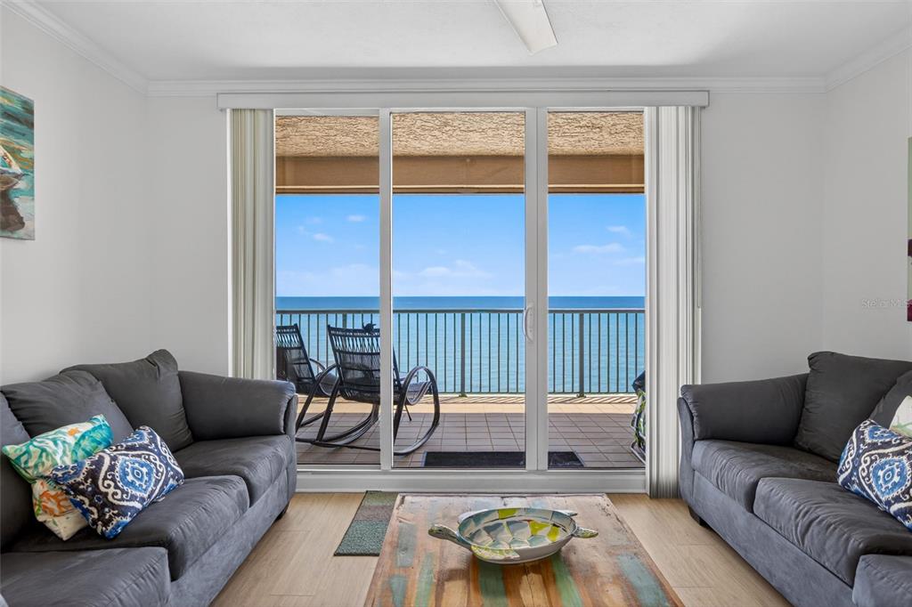 A living room with two gray sofas faces a sliding glass door overlooking the ocean — 3315 S ATLANTIC AVENUE UNIT 1406, DAYTONA BEACH SHORES, FL